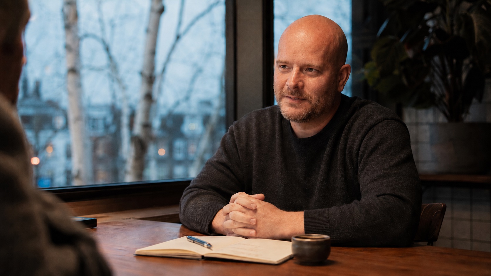 Danny Schuurman in gesprek aan een walnoten tafel in Amsterdam